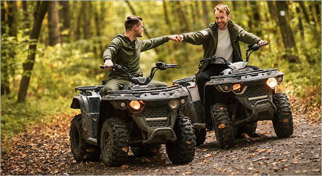 Zwei ATV-Fahrer mit grobstolligen Reifen auf einem Waldweg